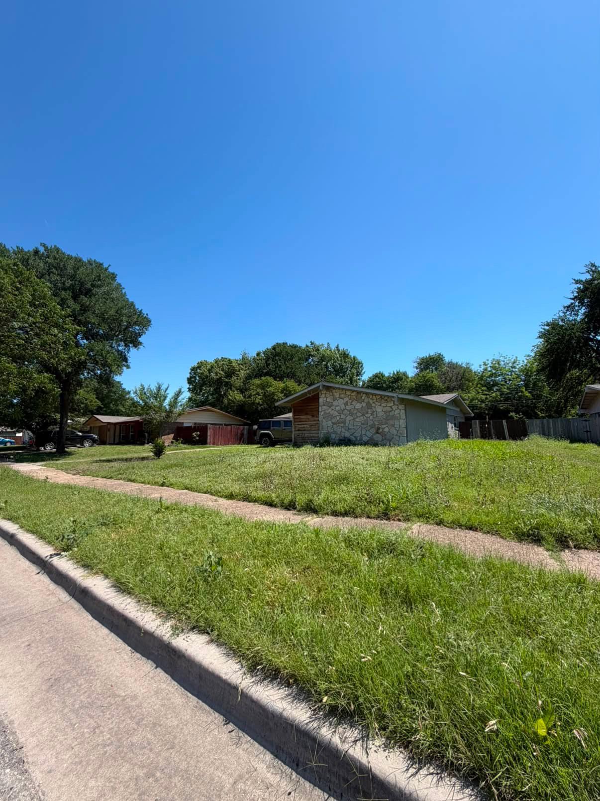 Overgrown corner lot mow, edge & sidewalk reclaim — before