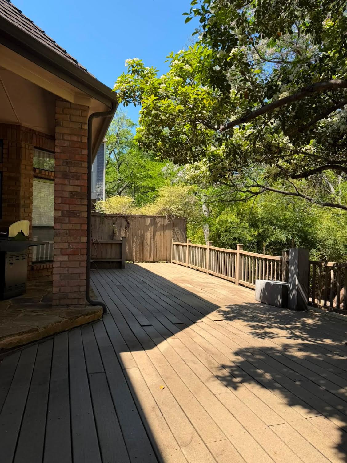 Wood backyard deck cleaned and restored beside a brick home